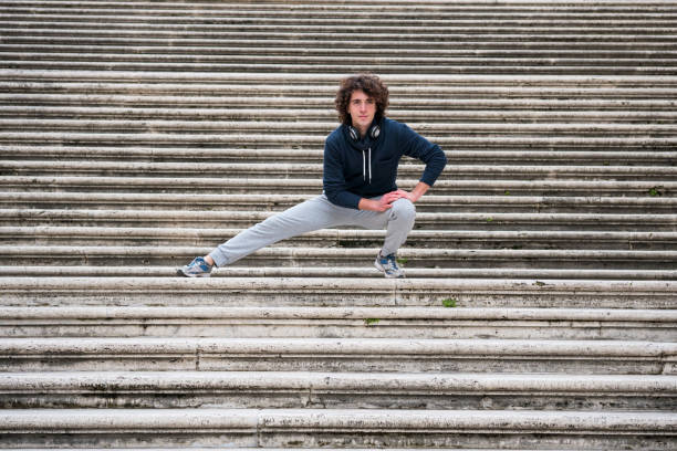 istock Handsome young sportsman stretching and warming-up for training on staircase 962678232