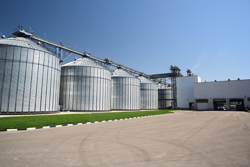 Animal feed factory. Big modern granary in sunny summer day. Metal containers for grain horizontal