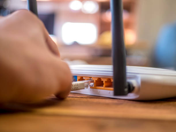 close up hand inserting ethernet wire in wi-fi router on wooden table - wooden hub imagens e fotografias de stock
