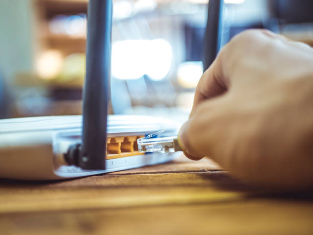 close up hand inserting ethernet wire in wi-fi router on wooden table - wooden hub imagens e fotografias de stock