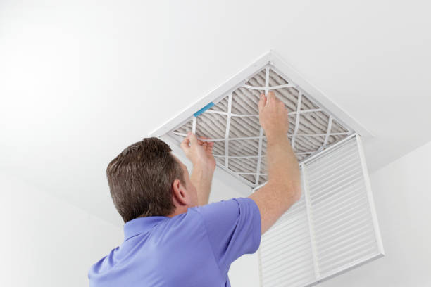 Person Removing Ceiling Air Filter Caucasian male removing a square pleated dirty air filter with both hands from a ceiling air duct. Guy taking out an unclean air filter from a home ceiling air vent. air duct photos stock pictures, royalty-free photos & images