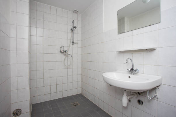 Simple, old clean bathroom with white tiled floor sink and shower stock photo