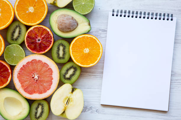 istock Different fresh fruits with blank notepad on white wooden table, top view. Summer background. Copy space. 962696702