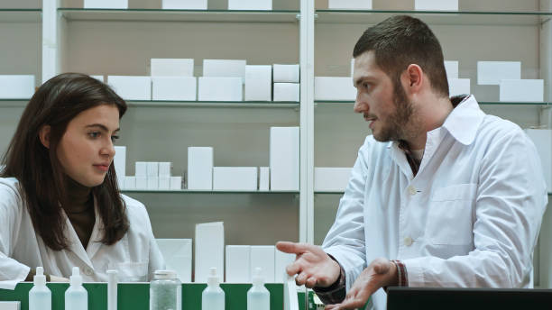 Two adult pharmacists having conflict, discussing problems at pharmacy