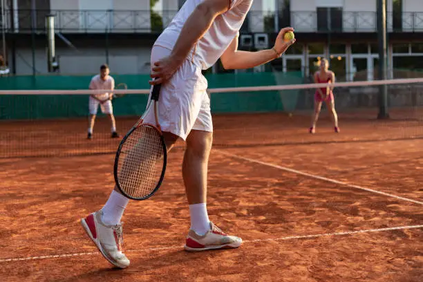Unrecognizable tennis player serving outdoor. Tennis player with racket during a match game prepares to serve a tennis ball