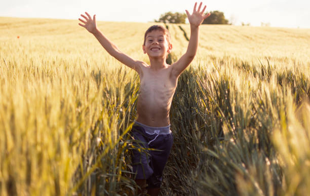 istock Poor boy without a shirt runs through the field of grain 962700872