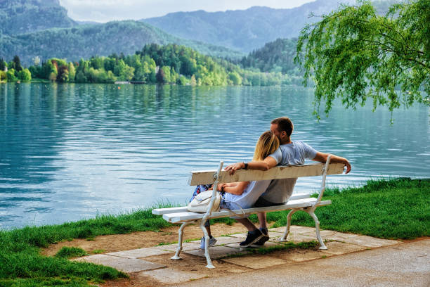 pareja romántica sentado sobre un banco en el lago de bled eslovenia - bench mountain park sitting fotografías e imágenes de stock