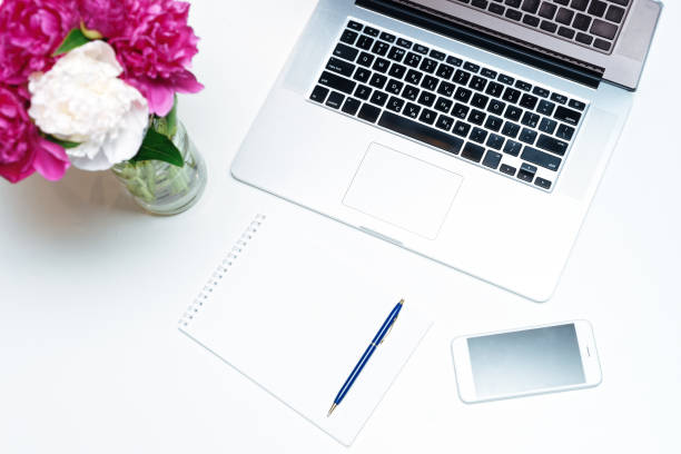 istock Workplace with laptop notebook pink white peony flowers pen 962702414