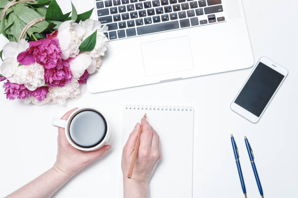 istock Workspace mobile phone laptop coffee and female hands pink peony 962702428