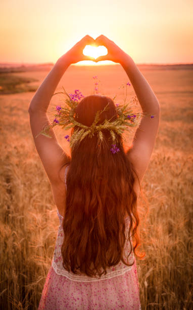 istock girl on wheat field making heart symbol at sunset 962705636