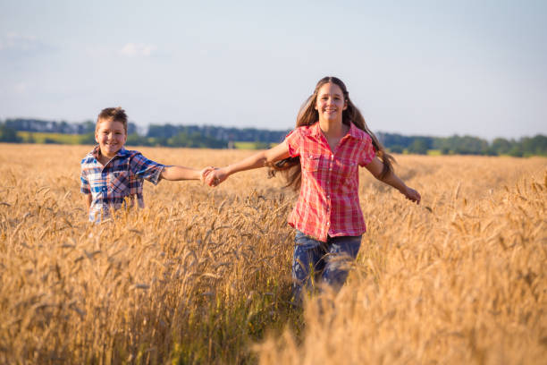 girl and boy running on field with ripe wheat - wheat freedom abundance human hand imagens e fotografias de stock