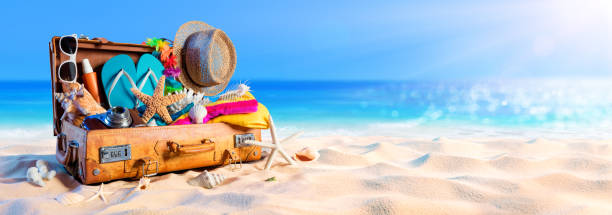 пляж подготовка - аксессуары в чемодане на песке - beach suitcase vacations summer стоковые фото и изображения