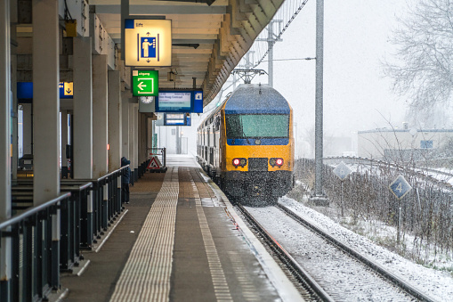 Amsterdam, Dutch train leaving a Amsterdam train station, towards Schiphol airport, during a snowy day.