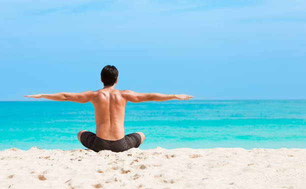 istock Young man practicing yoga at the beach 962713864