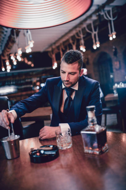uomo d'affari moderno che mette ghiaccio in bevanda alcolica - cigar whisky men smoking foto e immagini stock