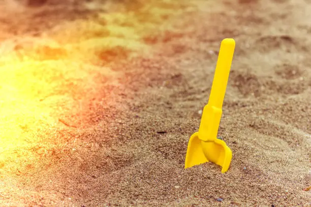 Photo of Children's shovel in the sand on the beach at sunset time