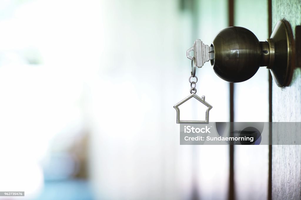 Home key with metal house keychain in keyhole, property concept Mortgage Loan Stock Photo