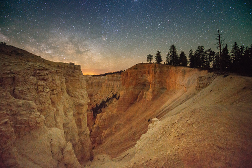 This is a horizontal, color photograph of Bryce Canyon National Park in Utah, USA at night with the Milky Way in the sky in springtime.