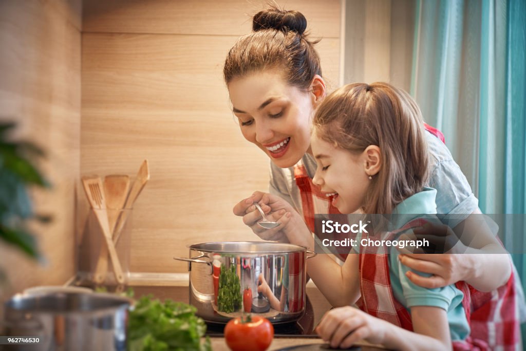 Happy family in the kitchen. Healthy food at home. Happy family in the kitchen. Mother and child daughter are preparing on the cooker. Cooking Stock Photo