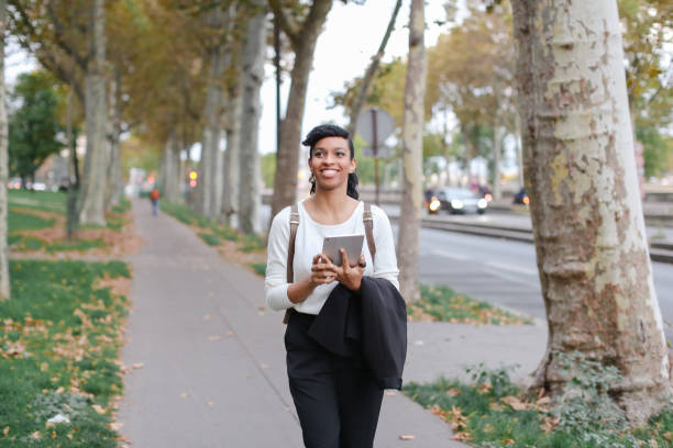 istock Beautiful black smiling student walking after classes with tablet on street with fallen leaves 962753776
