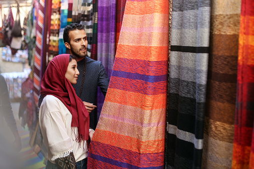 Smiling Arab couple looking at carpets. Both about 25 years old, Middle Eastern people.