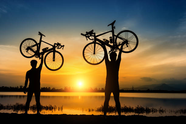 Silhouette two man stand in action lifting bicycle