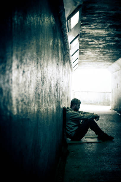istock Young lonely homeless man sitting in dark subway tunnel 962758542