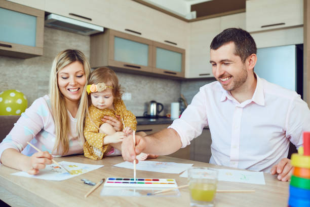 istock Mother, father and child draw together at the table 962765454