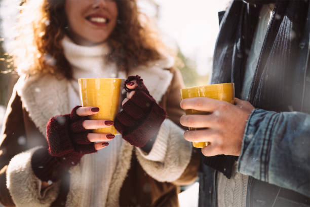 giovane coppia che beve cioccolata calda nella giornata di sole innevato - cold discussion outdoors snow foto e immagini stock