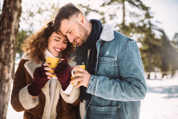 romantisches paar umarmt und trinken heiße schokolade im schnee - communication discussion coffee christmas stock-fotos und bilder