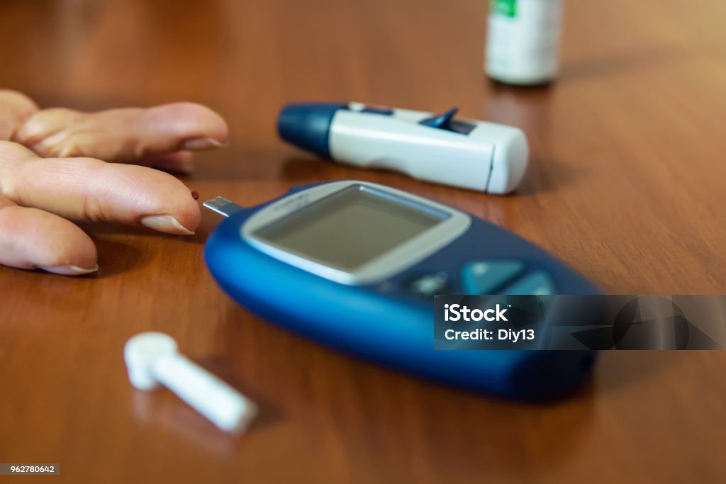 Testing for high blood sugar Testing for high blood sugar. Blood glucose meter and needles for the test lie on a wooden table. drop of blood on finger close up Diabetes Stock Photo