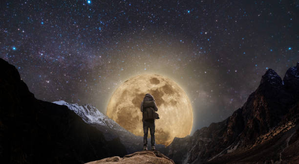 istock a man with backpack standing on mountain peak at night, and silhouette mountain with bright full moon and sky full of stars 962782630