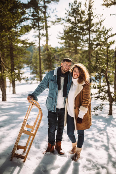 istock Happy friends with sledge standing in snow covered mountain forest 962788590