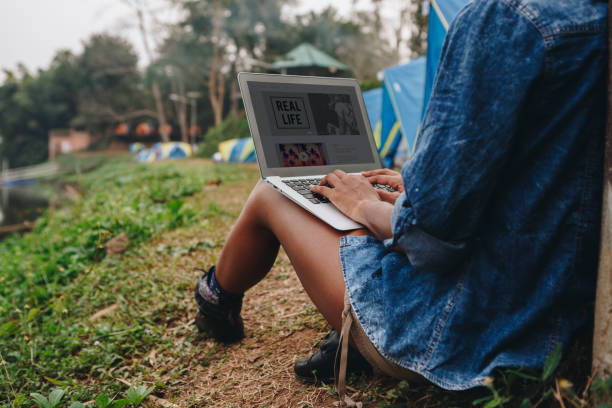 istock Woman alone in nature using a laptop on a camp site getaway from work or internet addiction concept 962790788