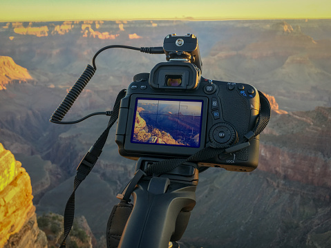 A DSLR camera in use to take pictures of a sunrise at Grand Canyon Mather Point on a sunny morning