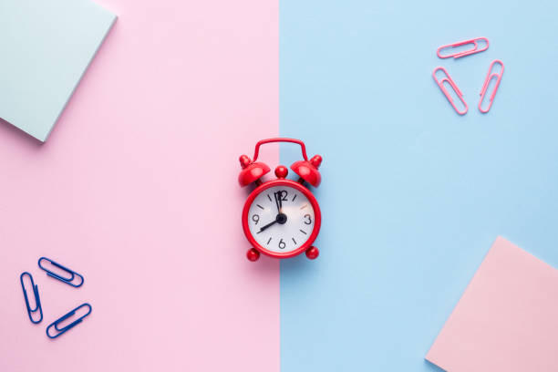 istock Flat lay on a pastel pink and blue background with a Notepad paperclip red alarm clock 962798838