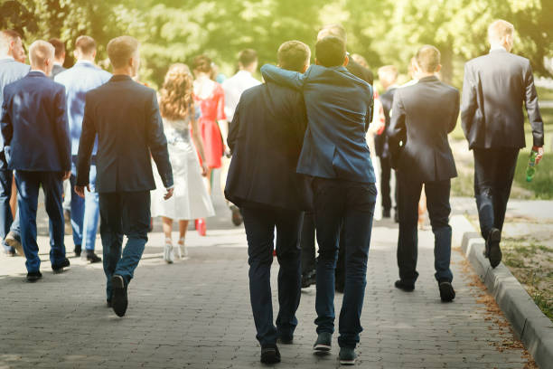 elegante uomo sicuro in giacca e cravatta che si diverte, gruppo di persone che camminano, ricevimento a matrimoni di lusso, ricca laurea a scuola o all'università - ballo di fine anno scolastico foto e immagini stock