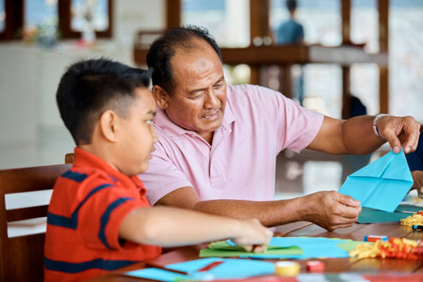 Grandfather teaching boy to make paper airplane
