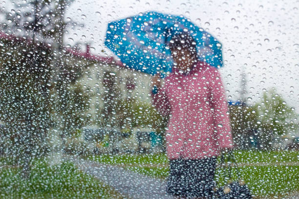 istock rain drops on glass with blurred background from man holding blue umbrella ,vintage 962804740
