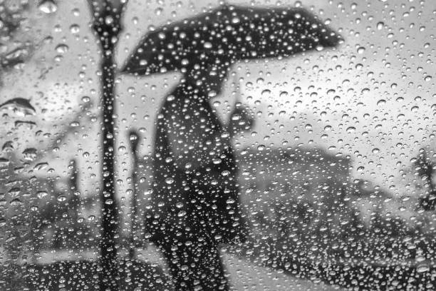 istock rain drops on glass with blurred background from man holding blue umbrella ,vintage 962804772