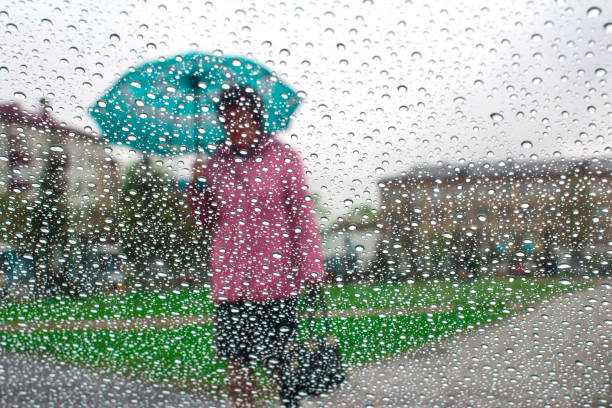 istock rain drops on glass with blurred background from man holding blue umbrella ,vintage 962804806