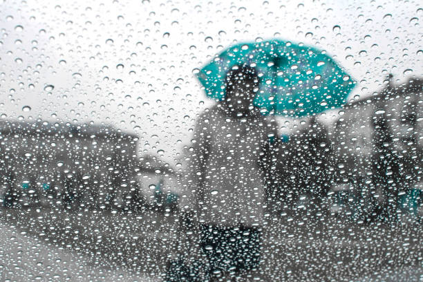 istock rain drops on glass with blurred background from man holding blue umbrella ,vintage 962804834