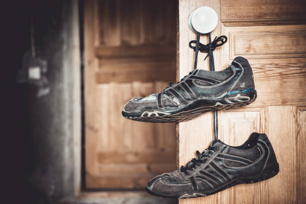 istock Old shabby sneakers, hang on a door. Grunge background. Copy space 962809302
