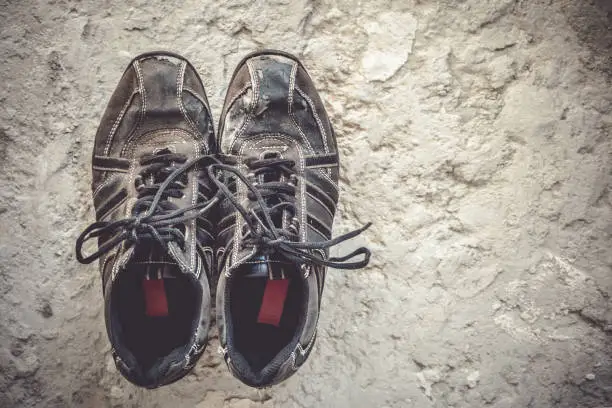 Old sneakers of black color stand on a concrete floor, top view. Copy space