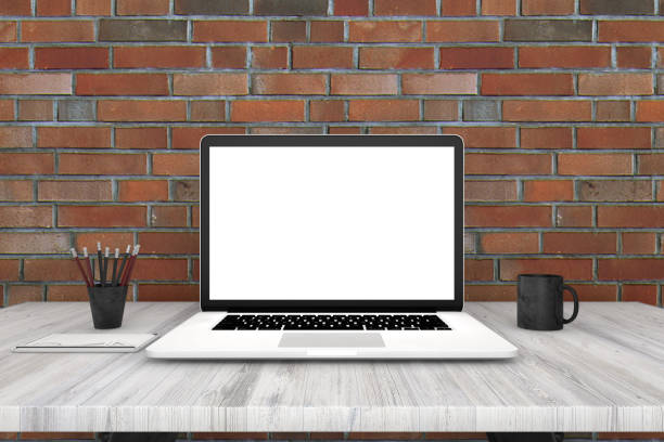 istock Laptop with blank screen on white desk, in front of brick wall 962811868