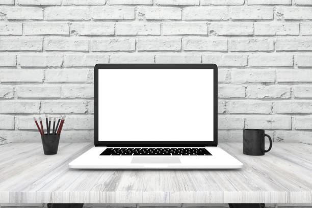 istock Laptop with blank screen on white desk, in front of brick wall 962812088