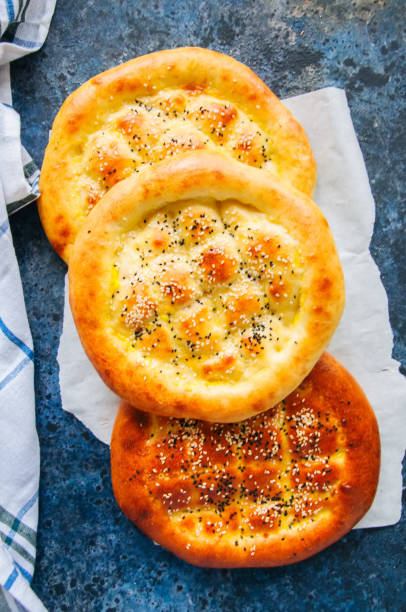 istock Turkish ramazan pidesi - Traditional Turkish ramadan flatbreads usually baked during ramadan month. Blue stone background. Top view. 962815416