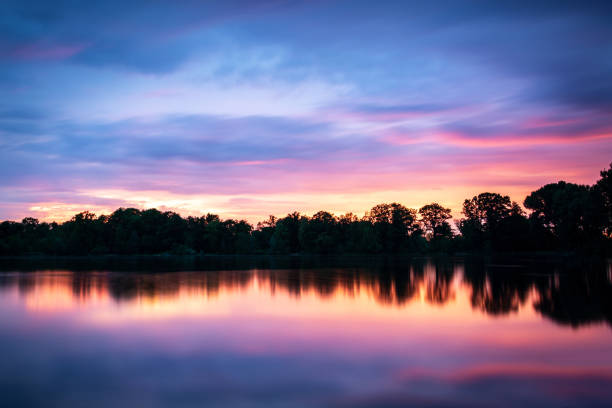Pink clouds after sunset and nice reflections over the lake Dutzendteich in Nuremberg