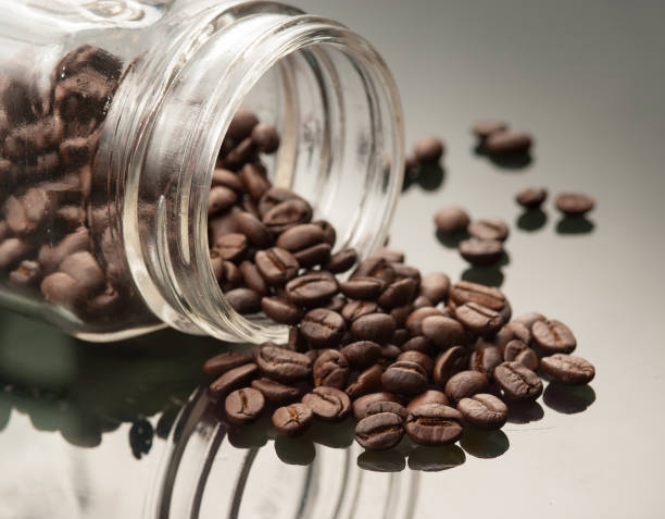 istock Coffee beans spilling out vintage glass jar with reflection 962817620