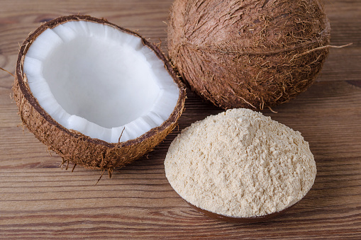 coconut flour in a bowl on brown wooden background